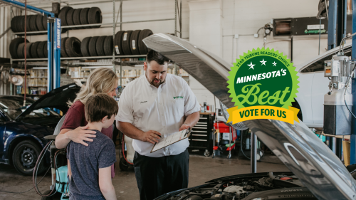 Mechanic discussing car service with family in auto repair shop, Minnesota's Best badge displayed.