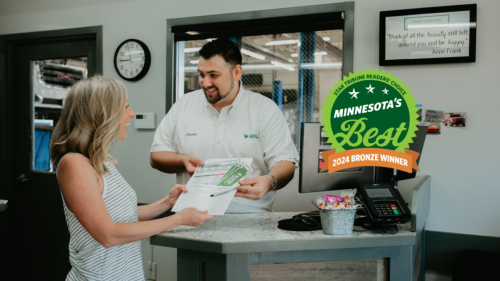 Customer smiling at service desk in award-winning Minnesota business. Minnesota's Best 2024 Bronze Winner badge displayed.