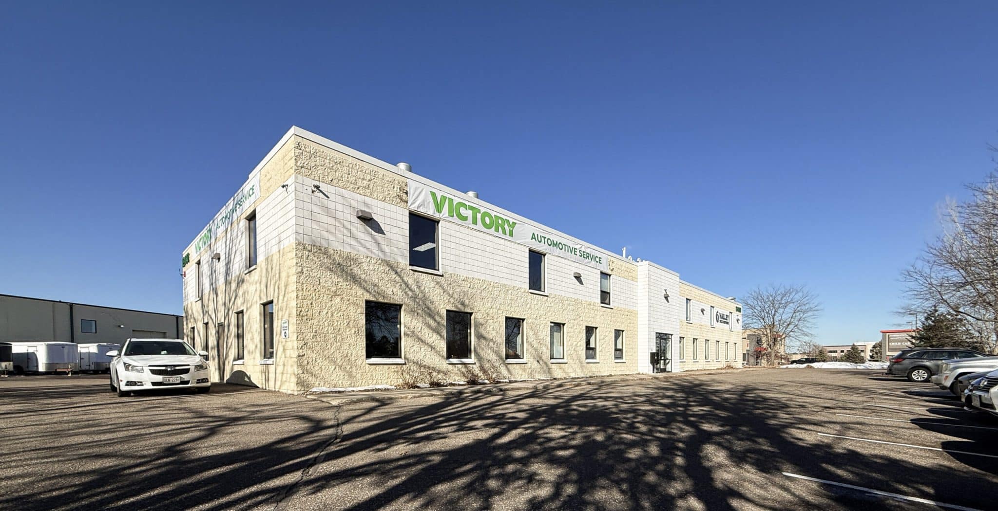 Victory Automotive Service building exterior with parking lot and blue sky background.
